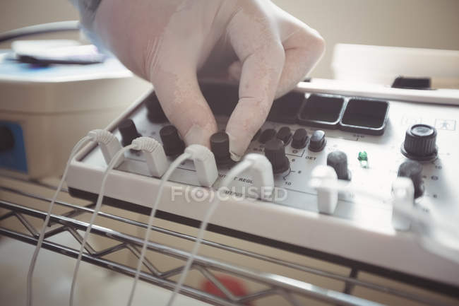Primo piano del dispositivo di elettrostimolazione di regolazione della mano maschile in clinica — Foto stock