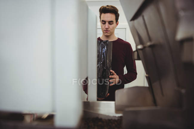 Мужчина держит мешок кофейных зерен в кофейне — стоковое фото