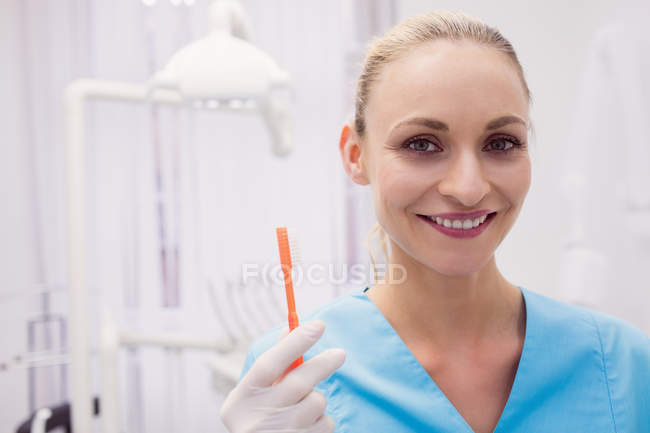 Ritratto di dentista donna che tiene lo spazzolino in clinica dentale — Foto stock