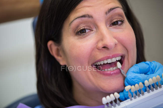 Dentista examinando paciente femenina con tonos de dientes en clínica dental - foto de stock
