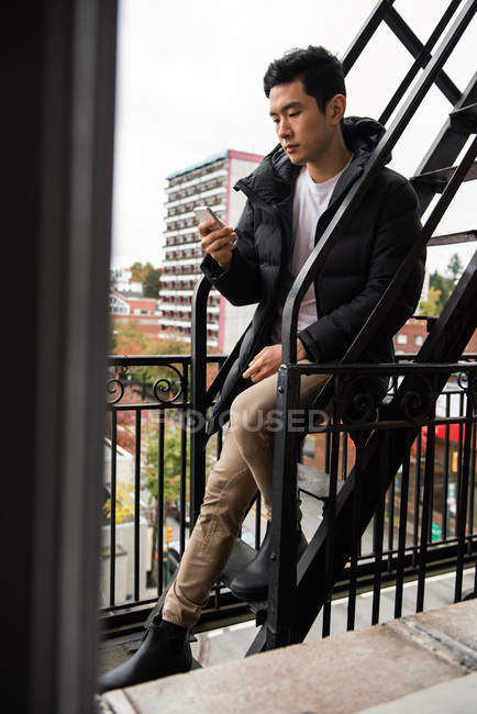 Hombre usando teléfono móvil en balcón - foto de stock