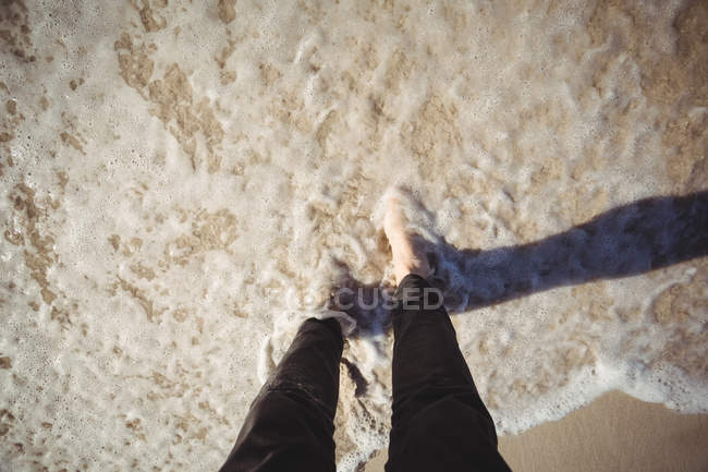 Baixa seção de uma mulher andando na água na praia — Fotografia de Stock