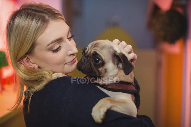 Woman carrying a pug puppy at dog care center — Stock Photo