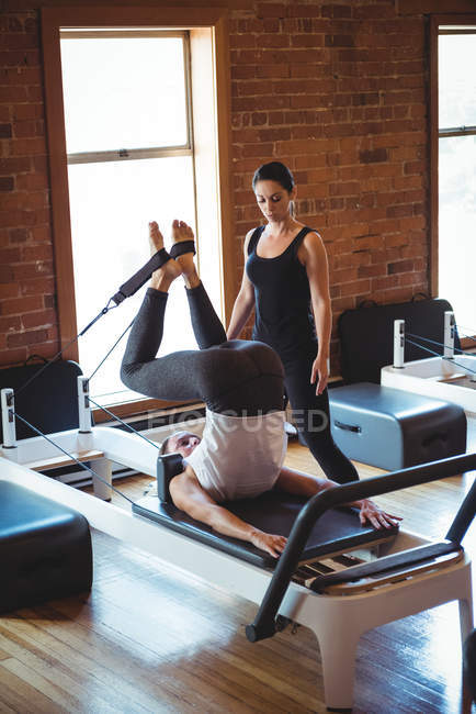 Coach helping a woman while practicing pilates in fitness studio — Stock Photo