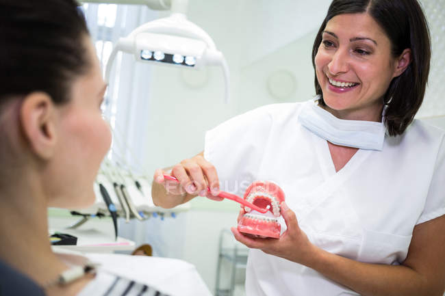 Стоматолог показує пацієнту, як чистити зуби в стоматологічній клініці — стокове фото