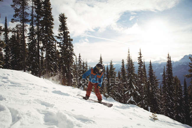 Чоловік катається на сноуборді на горі взимку проти дерев — стокове фото