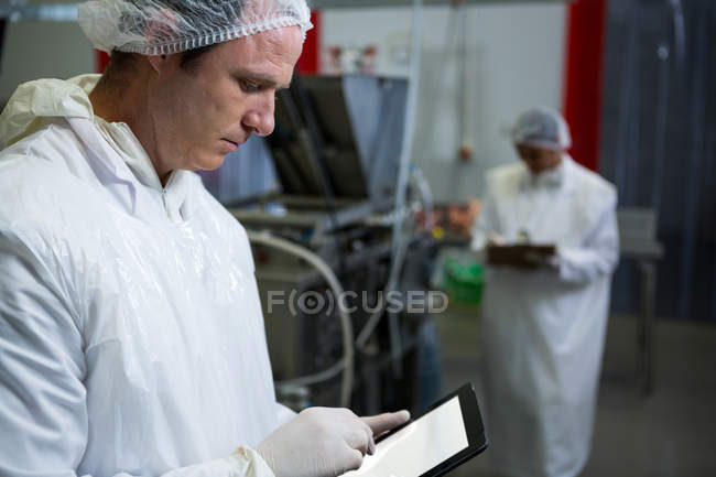 Male butcher using digital tablet at meat factory — Stock Photo