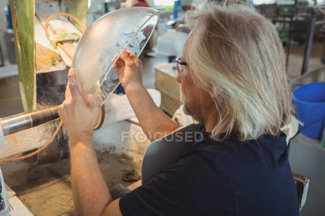 Soplador de vidrio pulido y molienda de una cristalería en la fábrica de soplado de vidrio - foto de stock