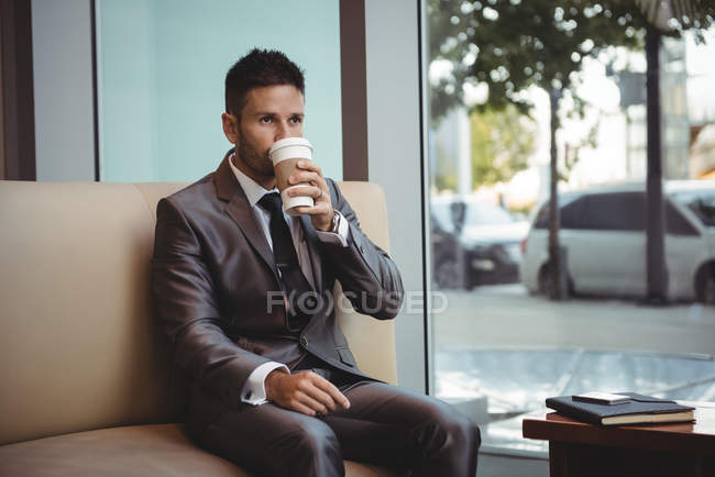 Geschäftsmann beim Kaffee auf dem Sofa im Büro — Stockfoto