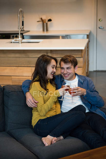 Пара п'є червоне вино, сидячи на дивані у вітальні вдома — стокове фото