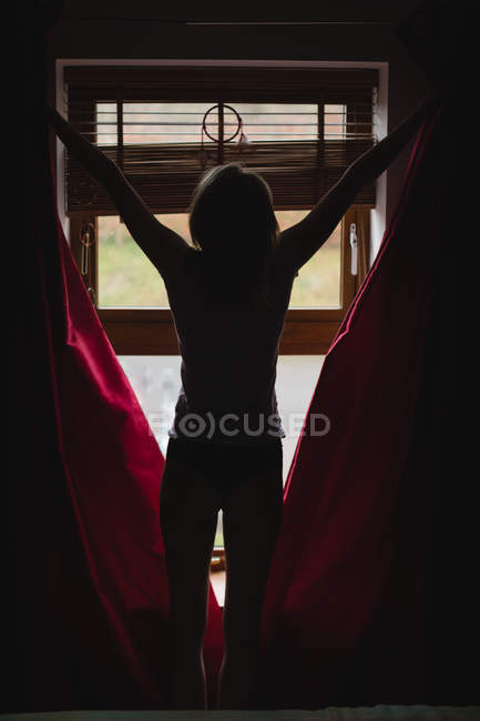 Frau öffnet Vorhänge im Schlafzimmer zu Hause — Stockfoto
