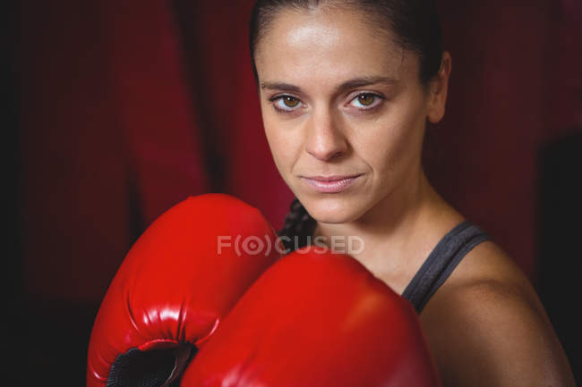 Уверенная женщина-боксер, занимающая боксерскую позицию в фитнес-студии — стоковое фото