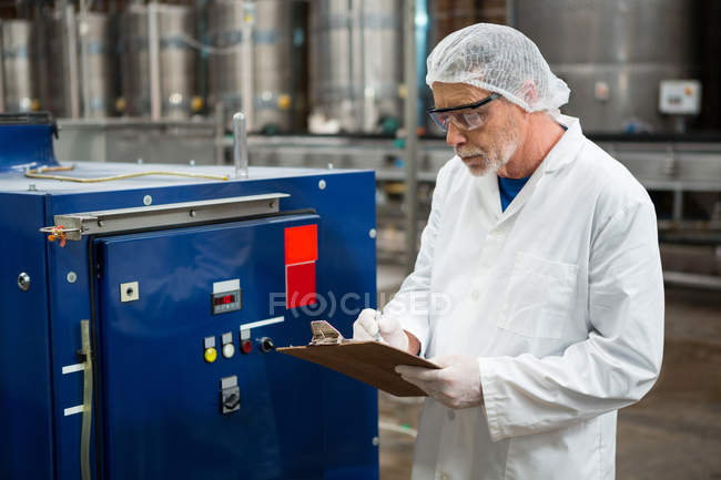 Serious male worker inspecting machines at cold drink factory — Stock Photo
