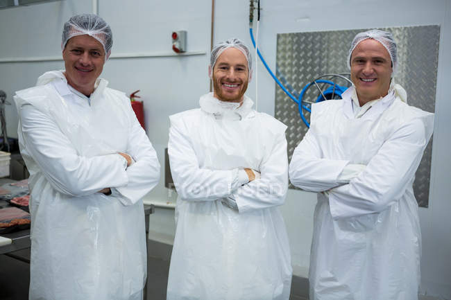 Équipe de bouchers debout avec les bras croisés à l'usine de viande — Photo de stock