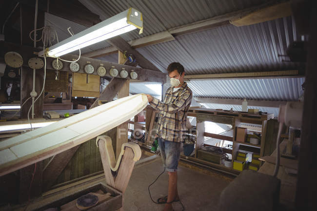 Hombre haciendo tabla de surf en el interior del taller - foto de stock