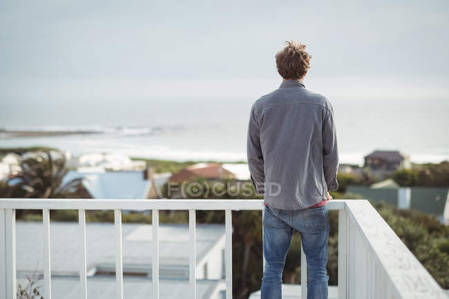 Вид сзади на человека, стоящего на балконе и смотрящего на вид — стоковое фото
