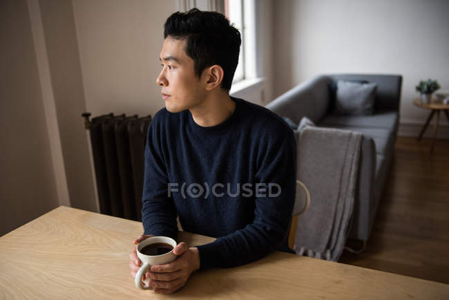 Вдумчивый человек держит чашку черного кофе дома — стоковое фото