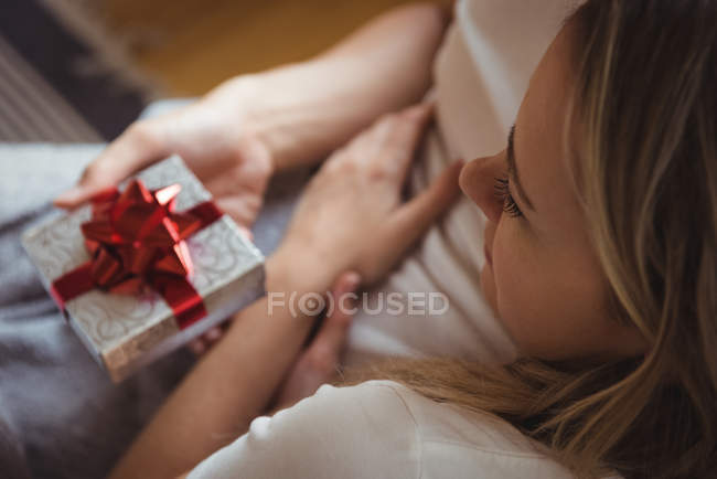 Casal romântico segurando caixa de presente na sala de estar — Fotografia de Stock
