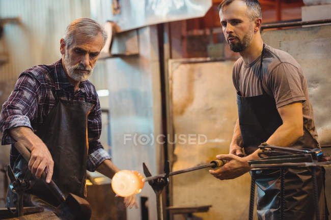 Team di soffiatori di vetro che formano e modellano un vetro fuso nella fabbrica di soffiaggio del vetro — Foto stock