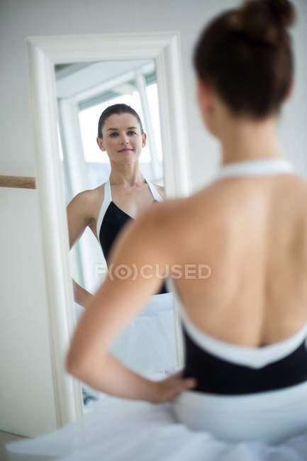 Балерина стоит перед зеркалом в балетной студии — стоковое фото