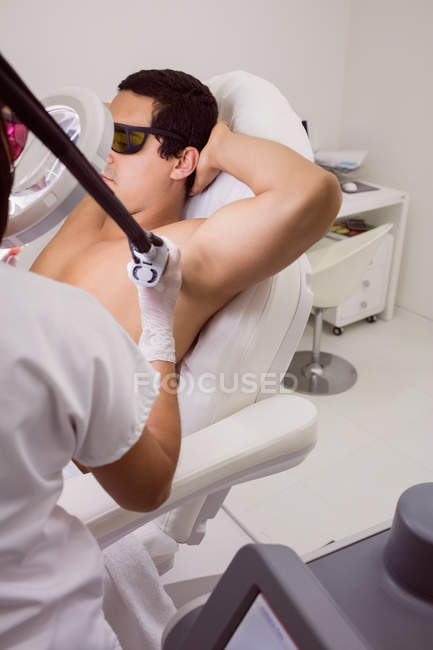 Médico realizando depilação a laser na pele da axila do paciente masculino na clínica — Fotografia de Stock