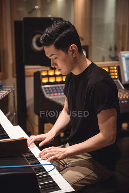 Hombre tocando un piano en un estudio de música - foto de stock