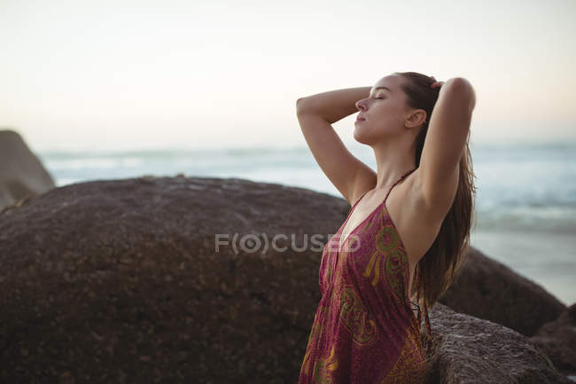 Блаженна жінка стоїть на пляжі в сонячний день — стокове фото