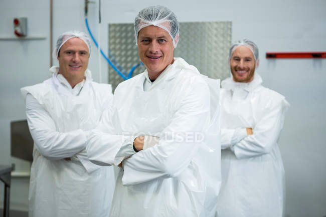 Squadra di macellai in piedi con le braccia incrociate in fabbrica di carne — Foto stock