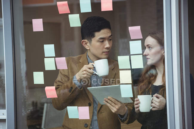 Führungskräfte diskutieren bei einer Tasse Kaffee im Büro über digitales Tablet — Stockfoto