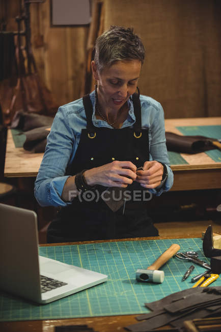 Handwerkerin bearbeitet in Werkstatt ein Stück Leder — Stockfoto
