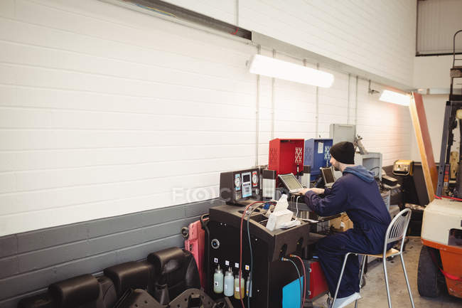 Meccanico utilizzando laptop in garage di riparazione — Foto stock