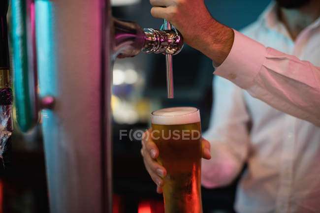 Primo piano del barista che riempie la birra dalla pompa del bar al bancone del bar — Foto stock