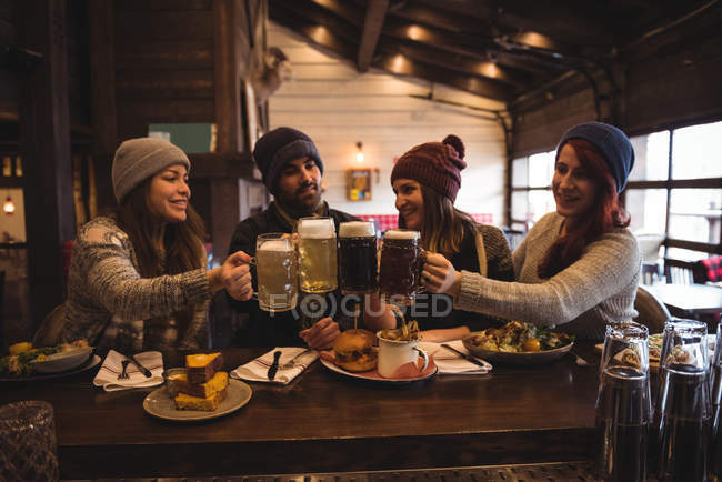 Счастливые друзья тосты с пивными бокалами в баре — стоковое фото