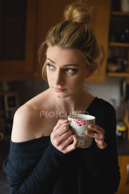 Продумана жінка тримає чашку кави на кухні вдома — стокове фото