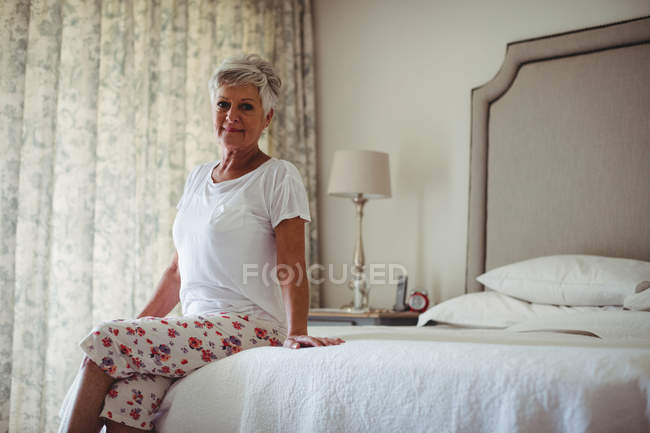 Портрет старшої жінки, що сидить на ліжку в спальні вдома — стокове фото