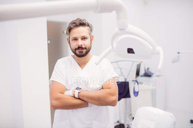 Dentista in piedi con le braccia incrociate in clinica — Foto stock