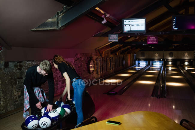 Due giovani che ordinano palle da bowling nella pista da bowling — Foto stock