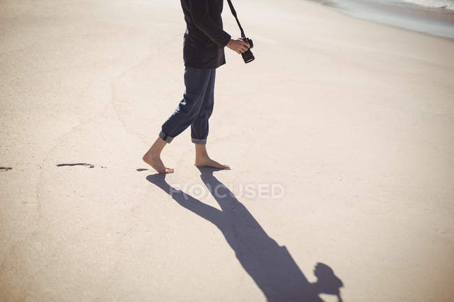 Mulher com câmera digital andando na praia de areia — Fotografia de Stock