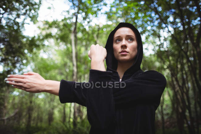 Femme effectuant un exercice d'étirement dans la forêt — Photo de stock