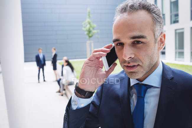 Бізнесмен розмовляє на мобільному телефоні поза офісною будівлею — стокове фото