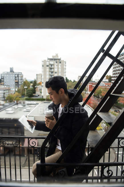 Mann schaut auf Laptop mit einer Tasse Kaffee auf dem Tisch zu Hause — Stockfoto