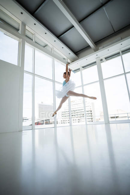 Ballerine pratiquant la danse de ballet en studio avec fenêtres — Photo de stock