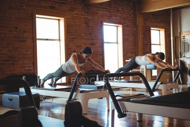 Mujeres practicando pilates en reformadores en gimnasio - foto de stock
