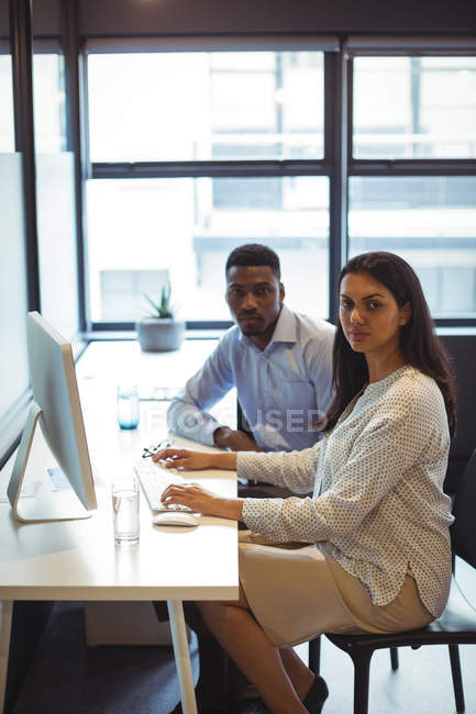 Portrait of businessman and a colleague working over computer in office — Stock Photo