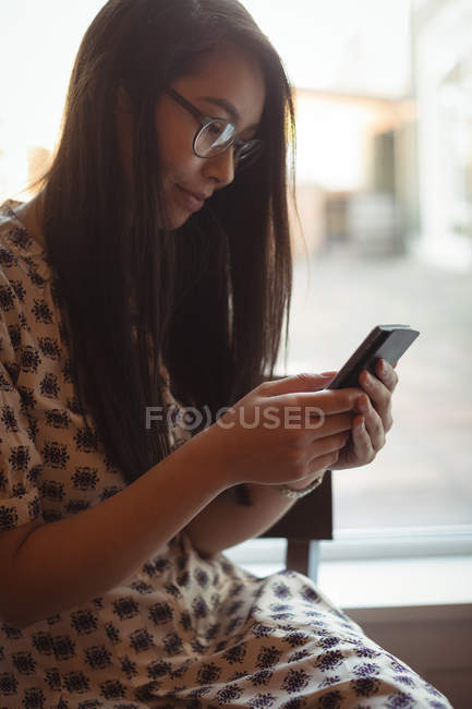 Жінка використовує мобільний телефон біля вікна в кафе — стокове фото