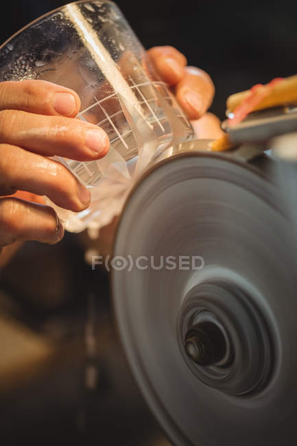Close-up of glassblower polishing and grinding a glassware at glassblowing factory — Stock Photo