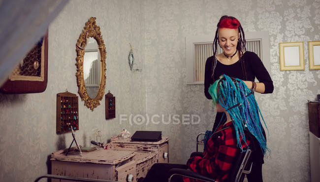 Beautician styling clients hair in dreadlocks shop — Stock Photo