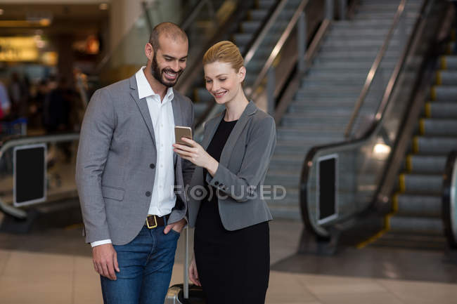 Glückliches Paar nutzt Handy am Flughafen — Stockfoto