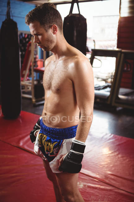 Boxer pensativo em pé no chão vermelho no estúdio de fitness — Fotografia de Stock