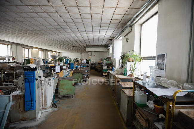 Estación de trabajo vacía y maquinaria en la fábrica de soplado de vidrio - foto de stock